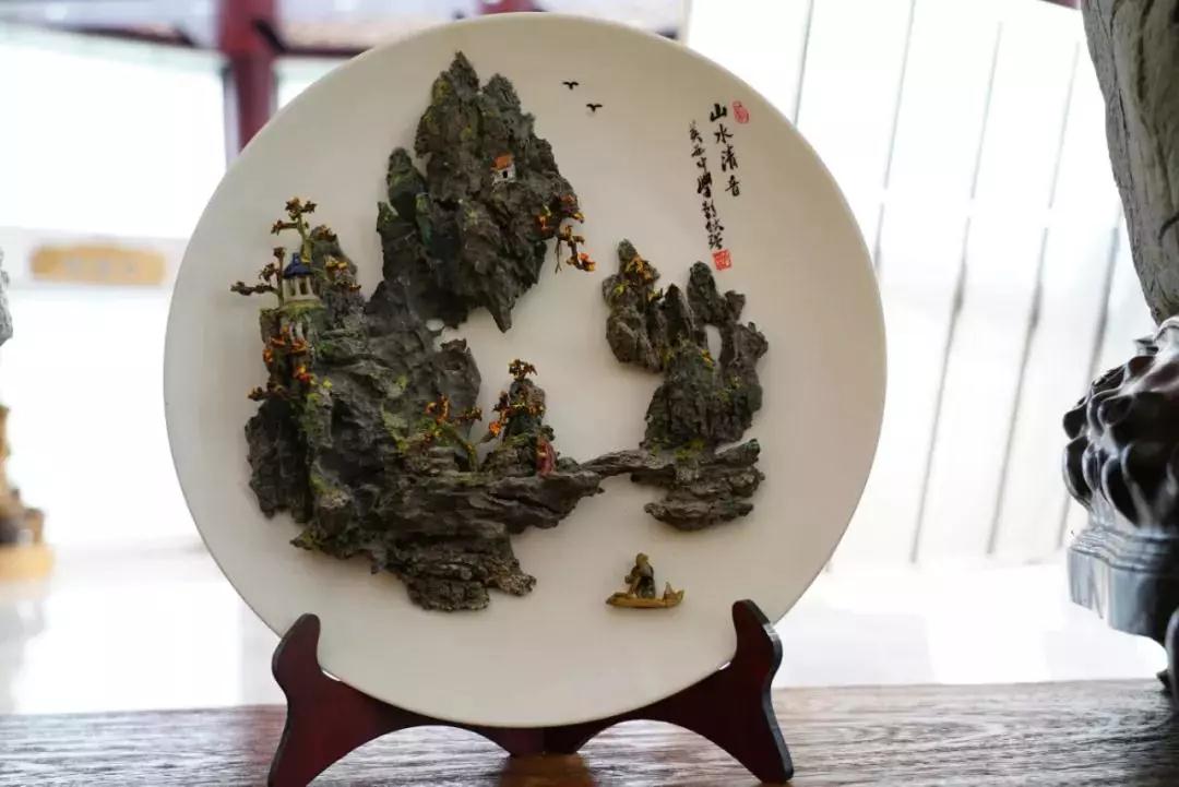 △ 英德的特产英石是一种层次感丰富的石灰岩，这是产业园内展示的英石山水盘景。（央视记者沈忱拍摄）